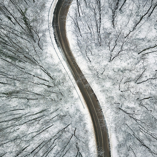 Snowy forest with a road. Aerial view.